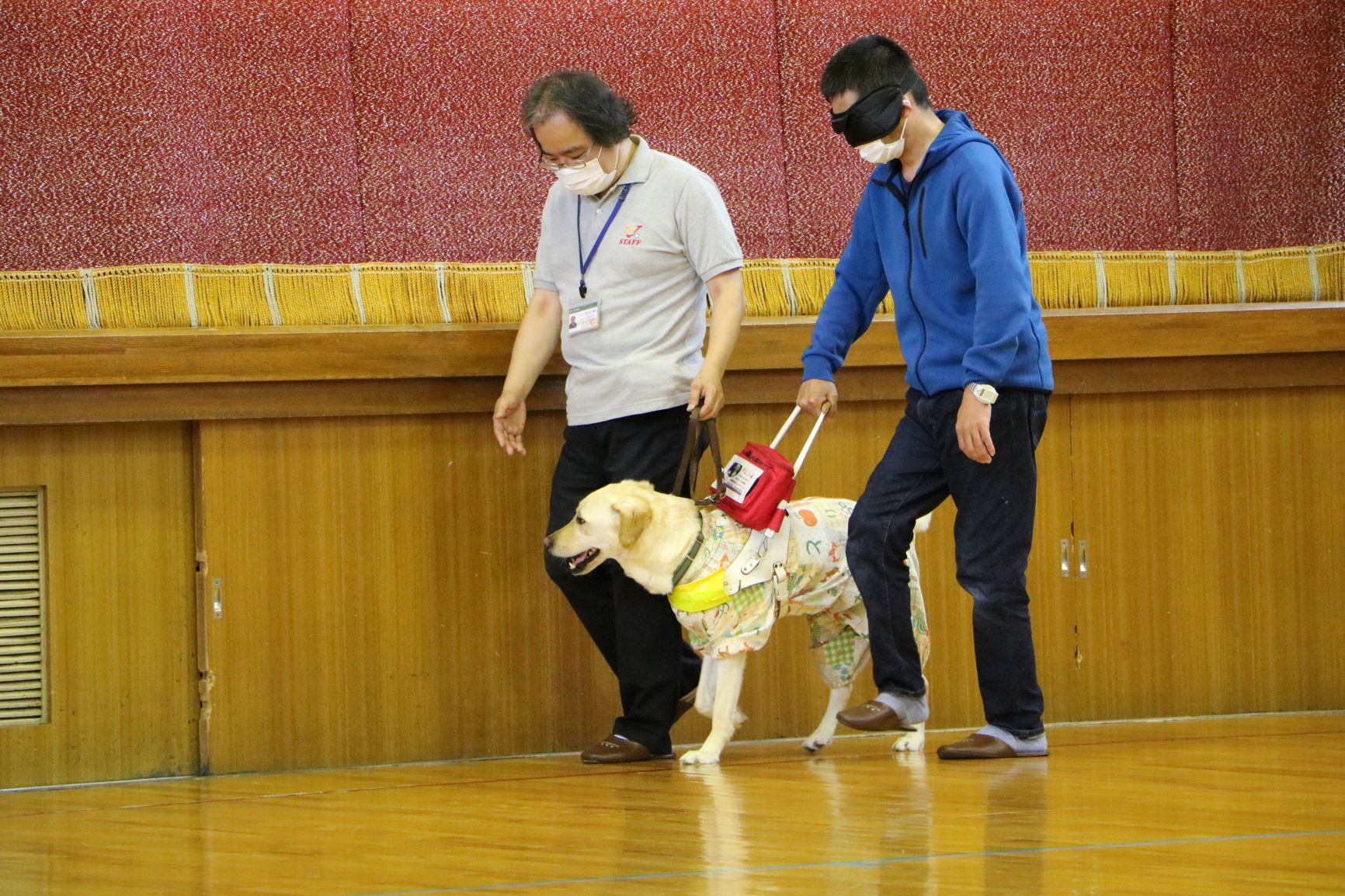 目隠しした状態で盲導犬の誘導を受ける参加者
